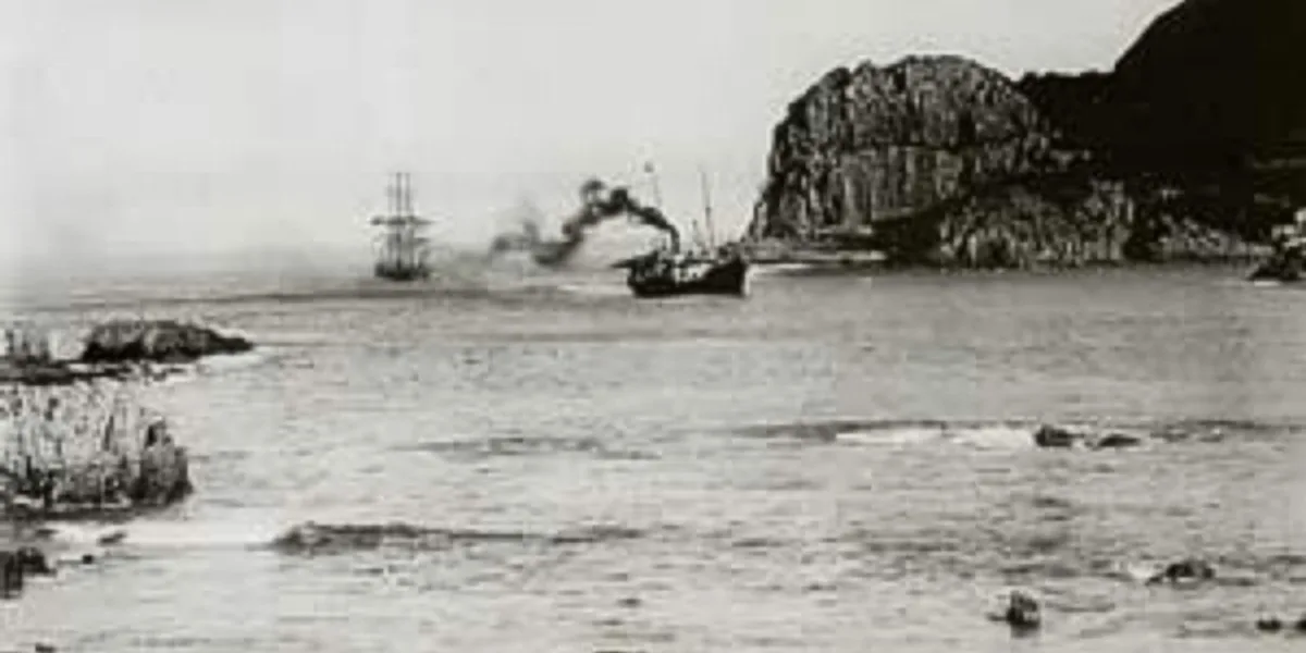 Black-and-white 1910 photograph of the steamship SS Agnar towing a sailing vessel through the Knysna Heads