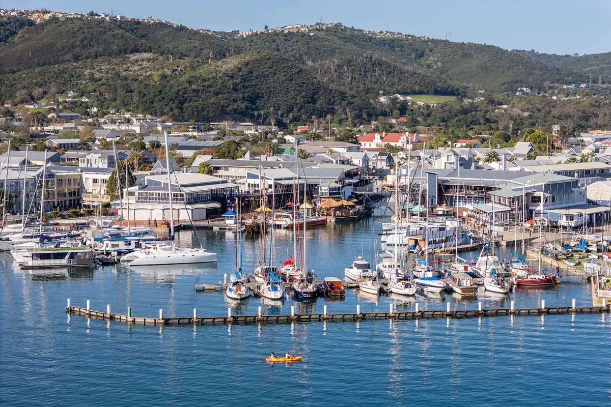 Knysna Quays from above — yachts moored along the marina pontoons with the lagoon and town beyond