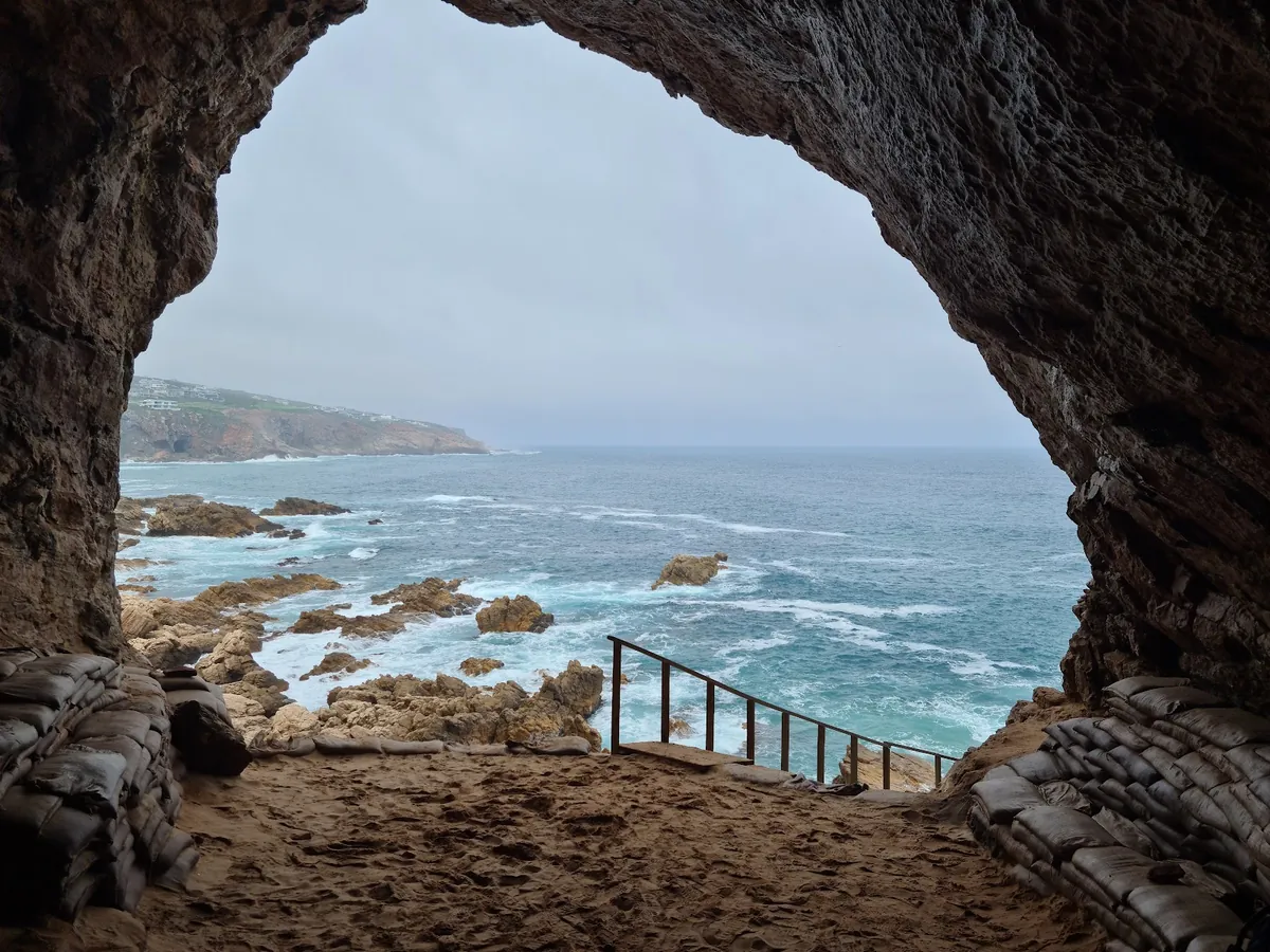 The view out of one of the Pinnacle Point caves near Mossel Bay, a walkway leading down to the rocky shore and ocean