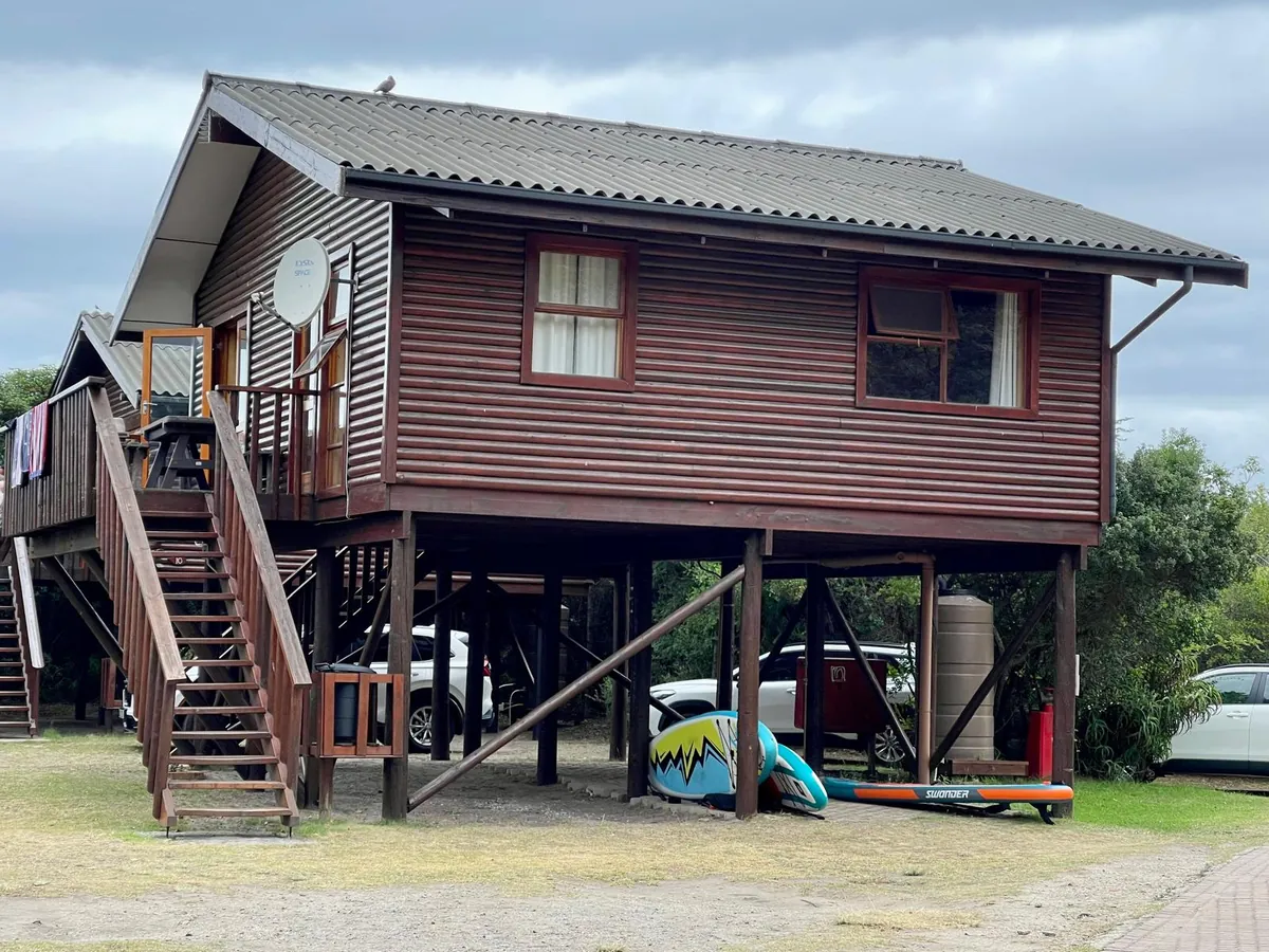 Ebb-and-Flow Rest Camp — timber chalets on stilts beside the Touw River, canoes stored underneath