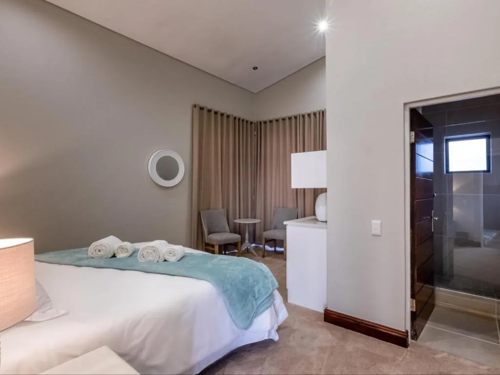 Spacious bedroom with queen bed, ensuite bathroom, and seating area