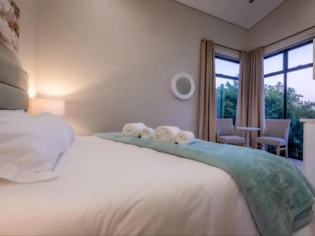 Spacious bedroom with king bed, rolled towels, garden views through large windows