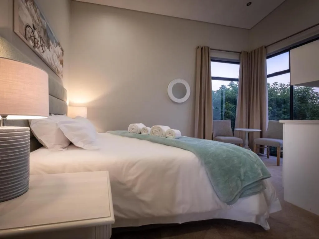Spacious bedroom with queen bed, fresh white linens, and garden views through large windows