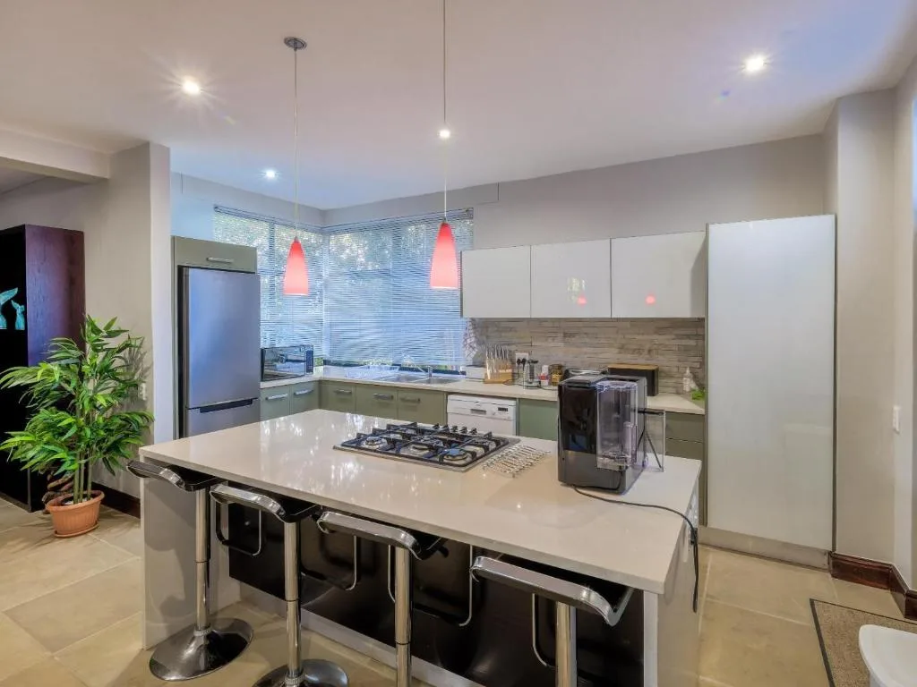 Modern kitchen with gas cooktop, white cabinetry, and pendant lighting overhead