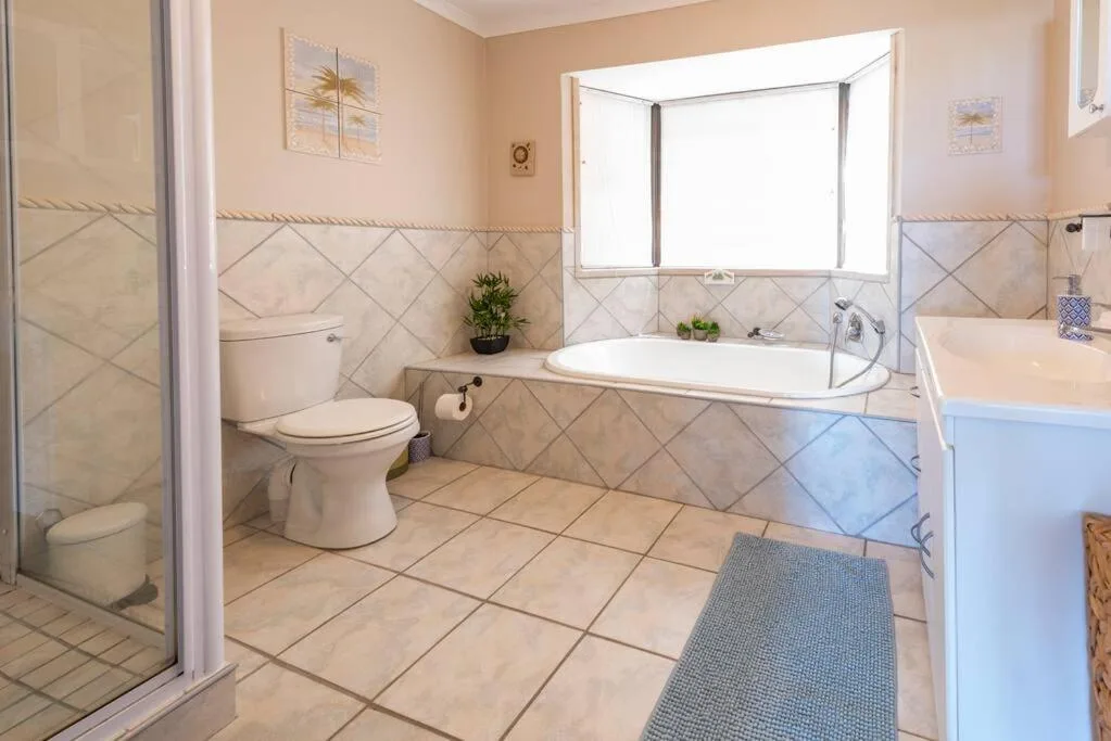 Spacious bathroom with bathtub, toilet, shower enclosure, and window