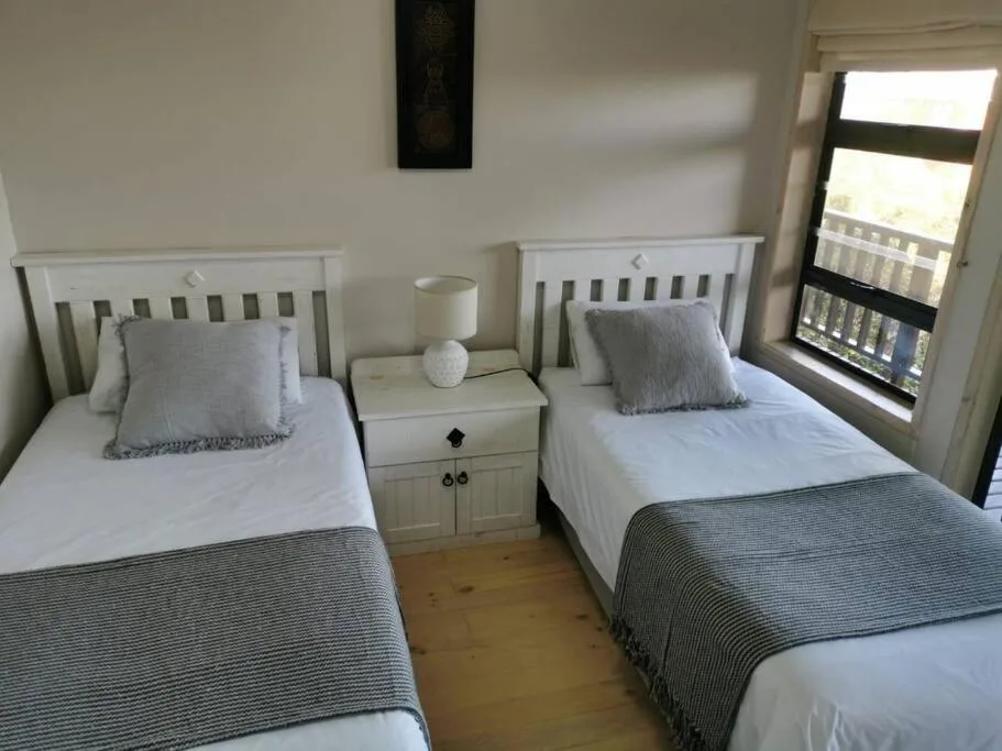 Twin beds with white headboards and gray striped throws in bright bedroom
