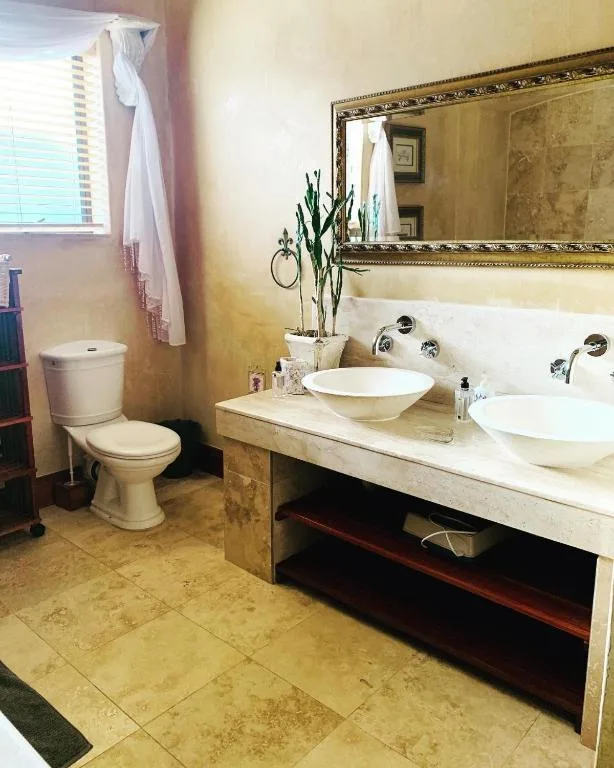 Elegant bathroom with dual vessel sinks, large mirror, and travertine flooring