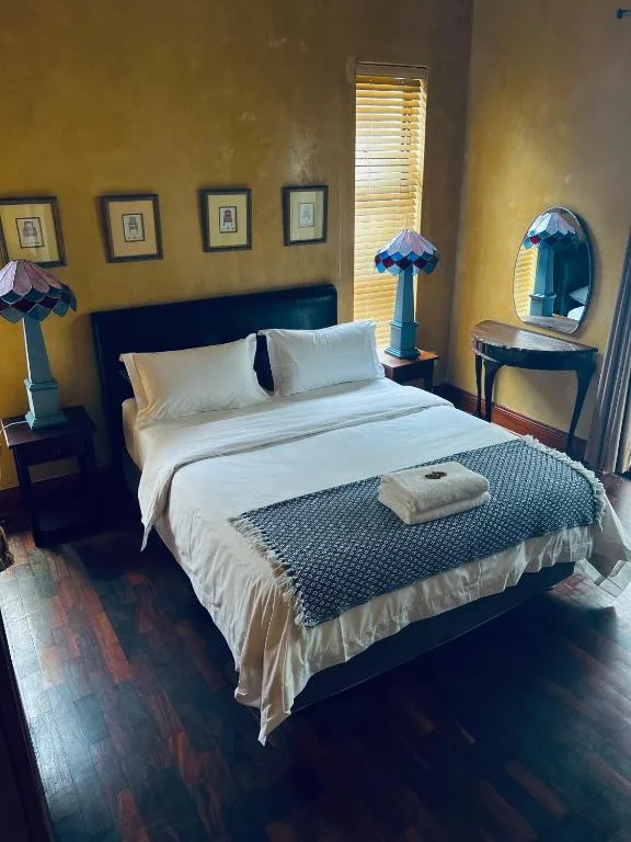 Bedroom with blue headboard, white bedding, yellow walls, and vanity mirror