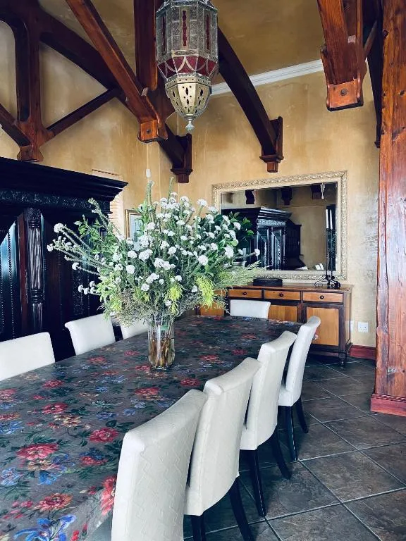 Elegant dining room with patterned table, white chairs, wooden beams