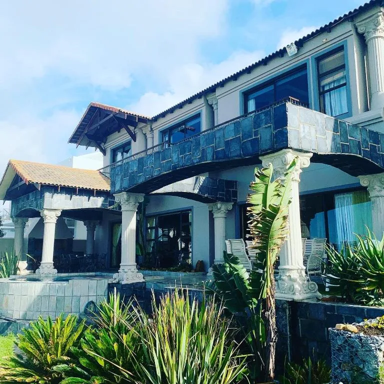 Charming blue colonial building with decorative columns and balcony railing.