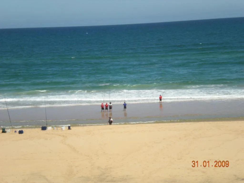 Sandy beach with turquoise ocean waves and swimmers enjoying the water