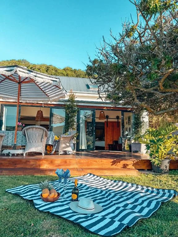Wooden deck with striped awning and outdoor seating area overlooking gardens