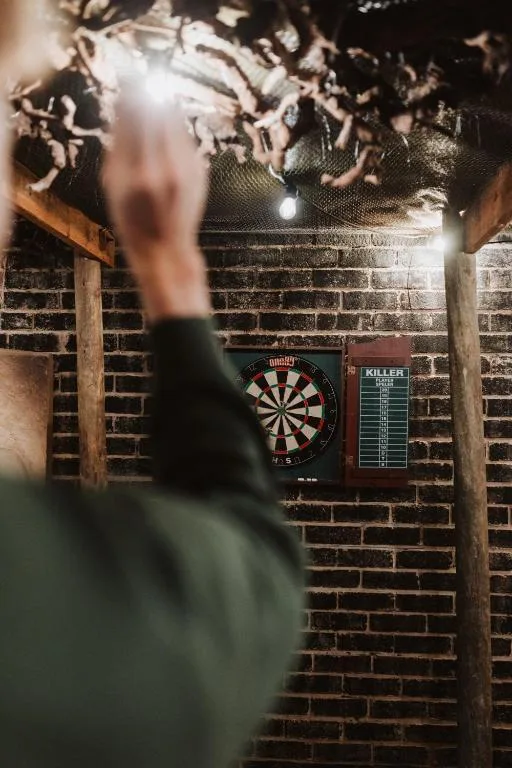 Dartboard and scoreboard mounted on rustic brick wall indoors