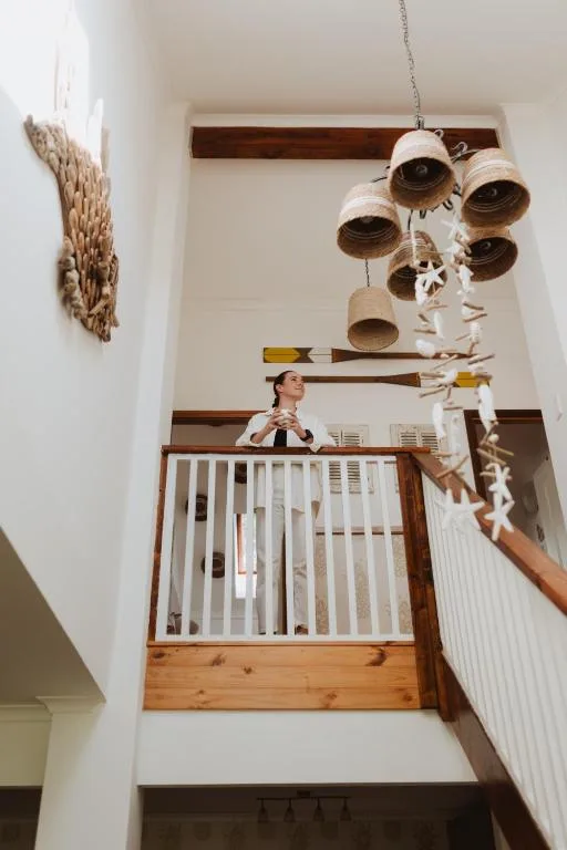 Hanging woven basket mobile and coastal-themed decor above wooden staircase