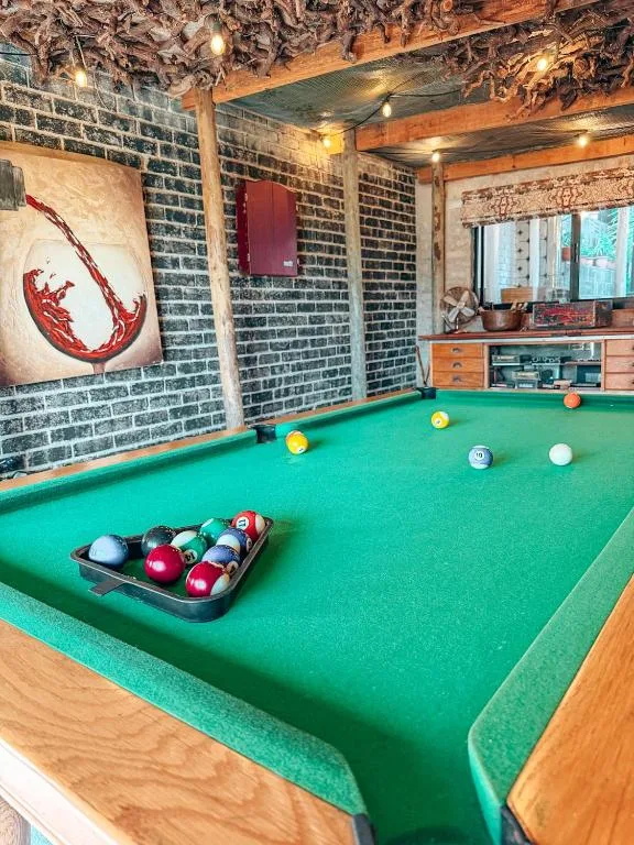 Indoor pool table with balls racked, rustic brick walls, warm lighting