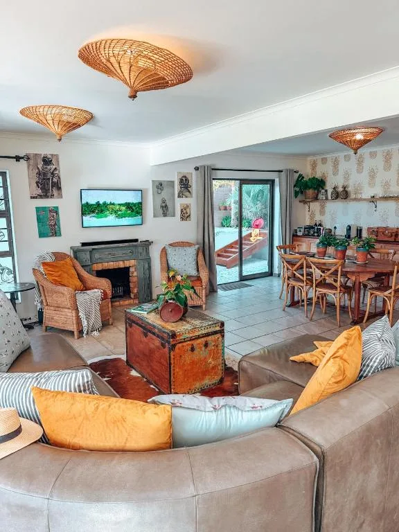 Open-plan lounge with curved sofa, fireplace, woven ceiling fixtures, and garden views