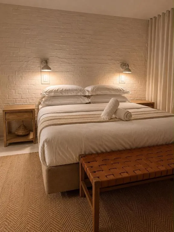 Modern bedroom with queen bed, cream bedding, and brick accent wall lighting