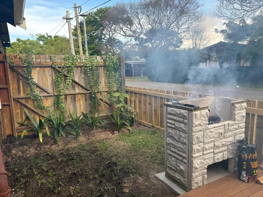Outdoor braai area with stone fireplace and wooden fence garden