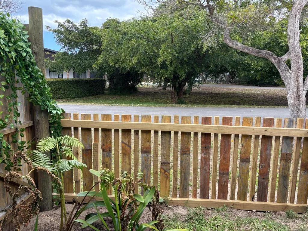 Wooden deck railing overlooking garden with mature trees and vegetation
