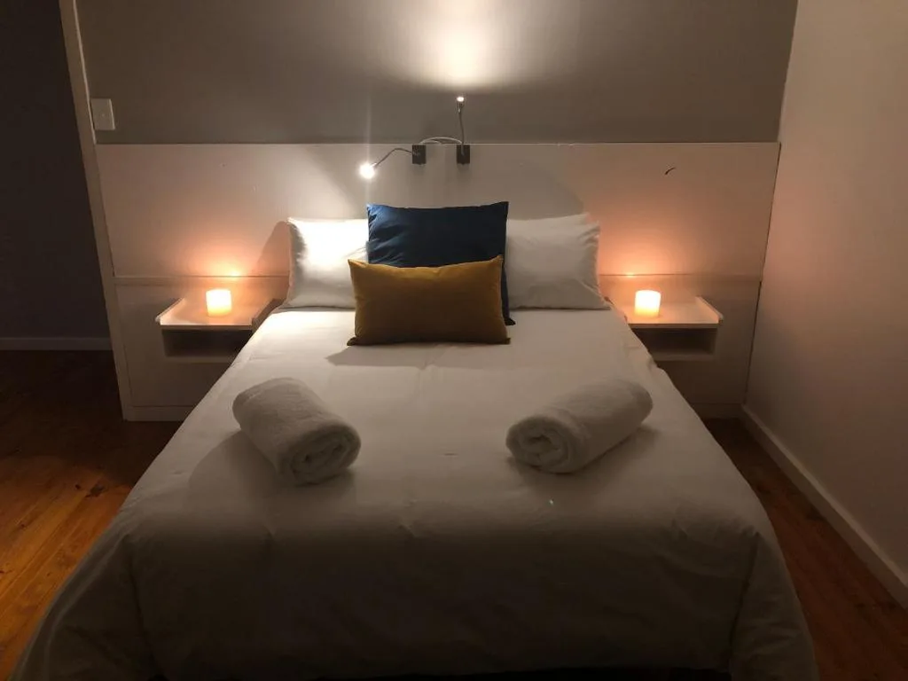 Modern bedroom with queen bed, colorful pillows, warm bedside lamps, and rolled towels