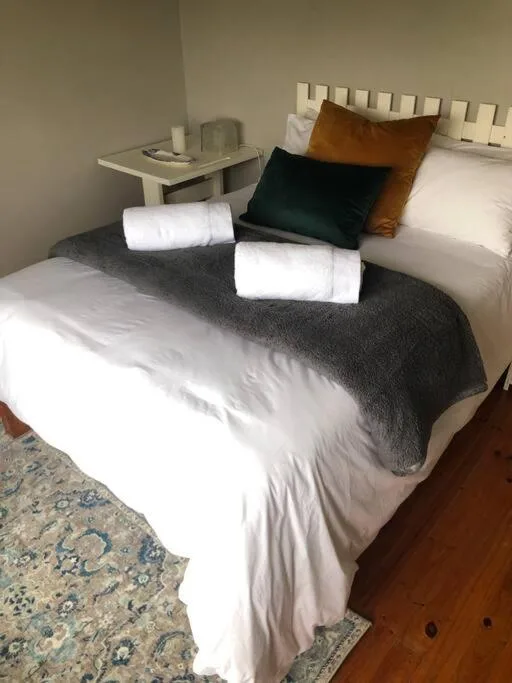 Neatly made bed with white linens, decorative pillows, and rolled towels