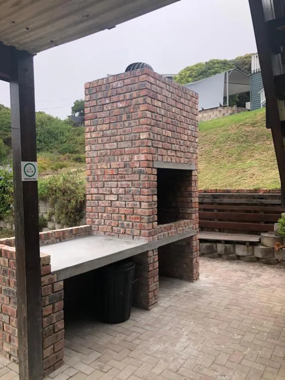 Outdoor brick braai area with seating on paved patio deck