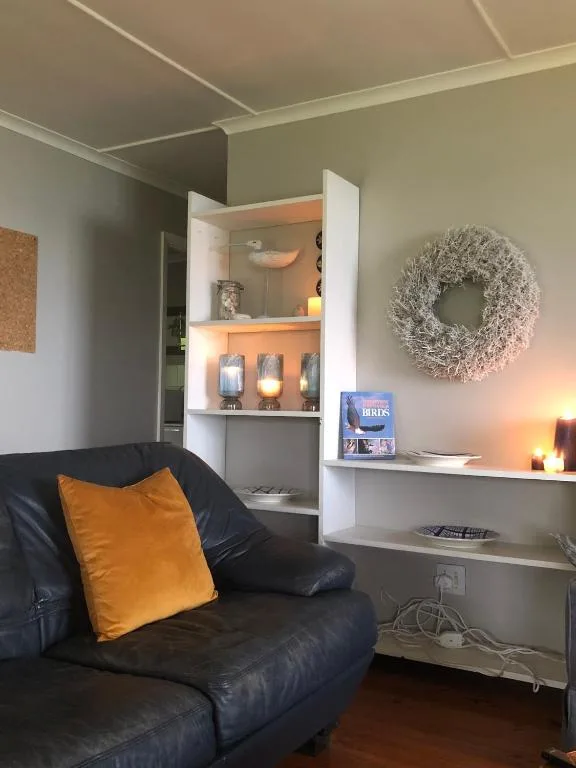 Cozy lounge with black leather sofa, orange accent pillow, and white shelving