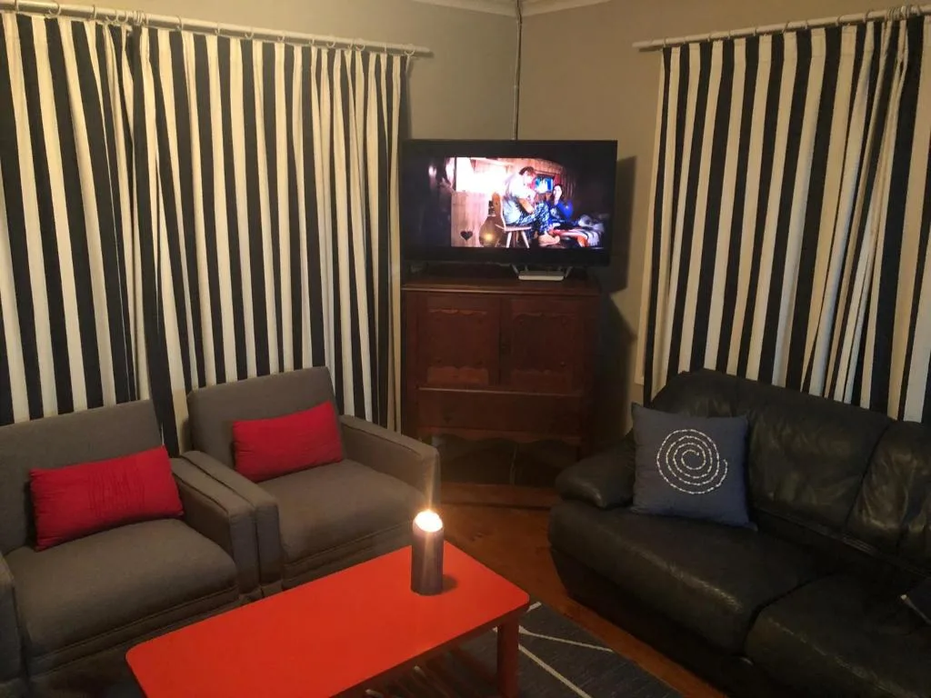Modern lounge with striped curtains, grey and black seating, red coffee table