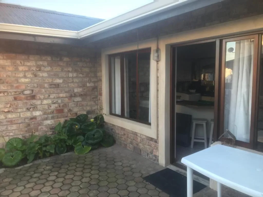 Covered patio area with brick walls, sliding glass doors, and outdoor seating
