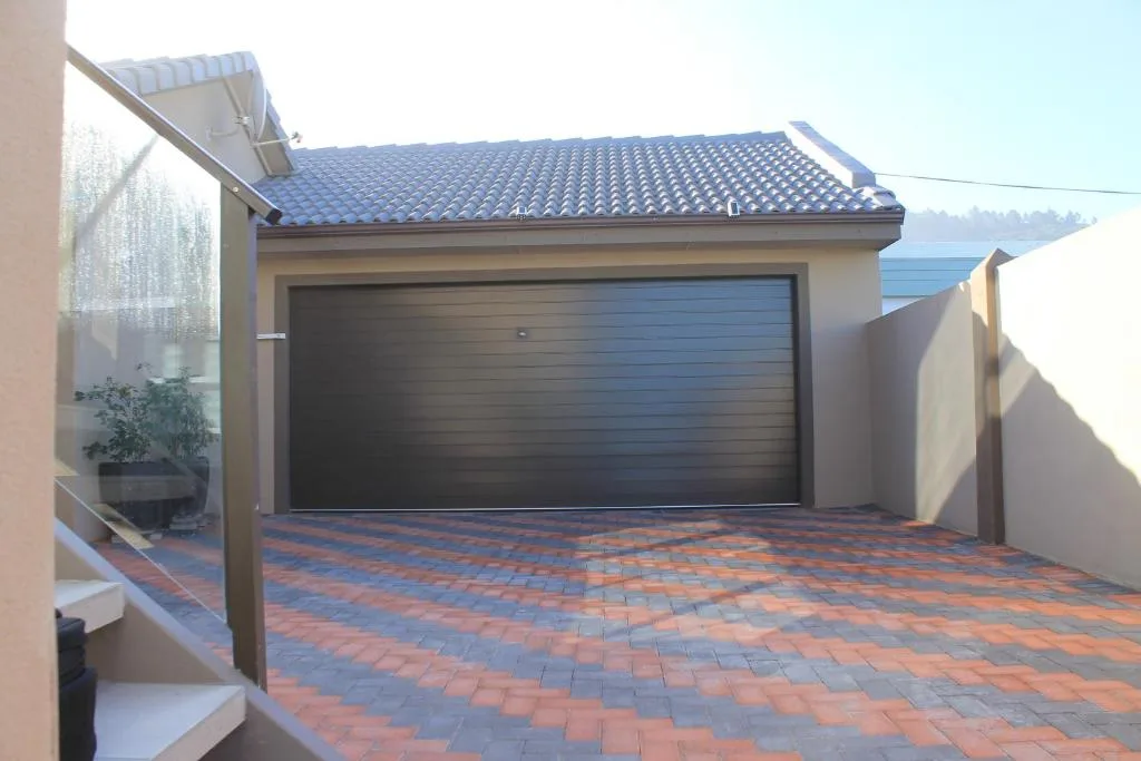 Modern garage and driveway with brick paving and pergola structure