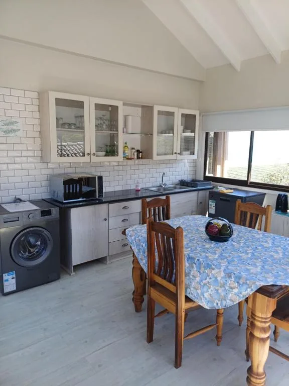 Open-plan kitchen with white cabinetry, dining table, and washing machine