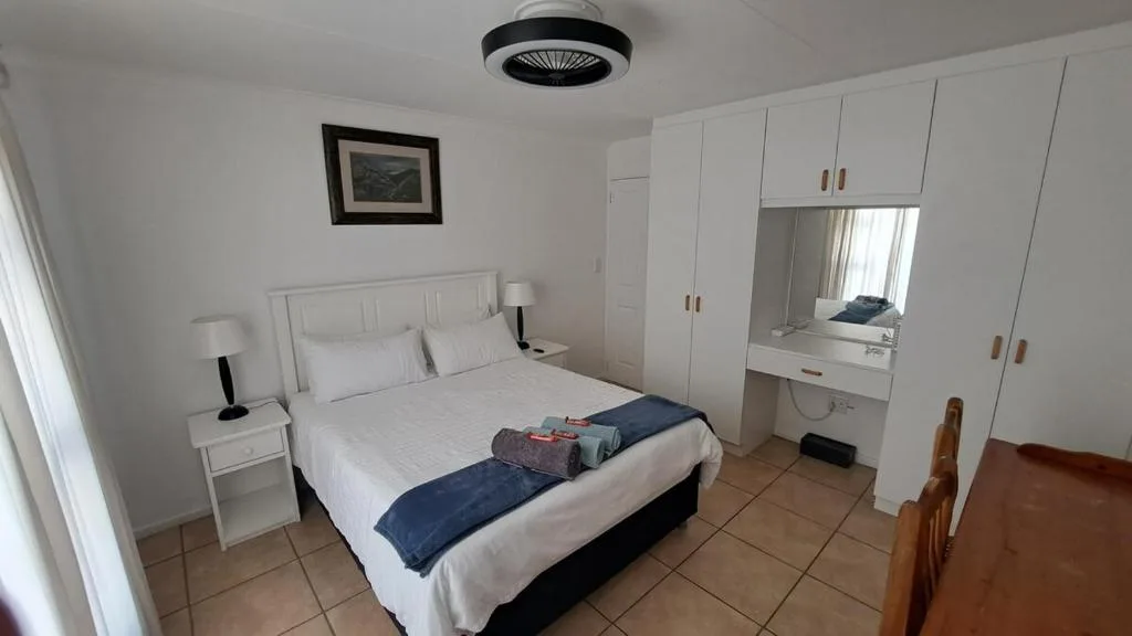 Spacious bedroom with queen bed, white built-in wardrobes, and vanity mirror