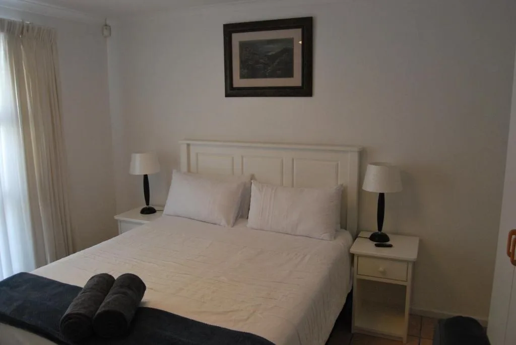 Bright bedroom with cream bed, side tables, and matching lamps