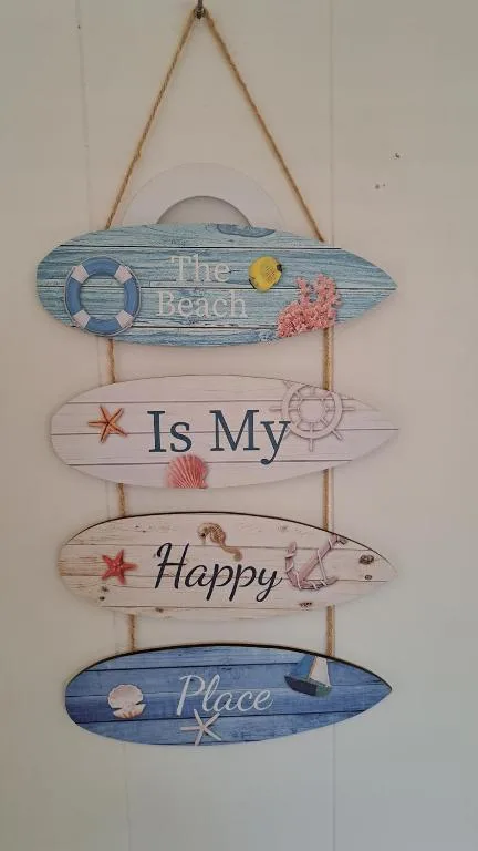 Coastal-themed wooden wall sign reading 'The Beach Is My Happy Place' with decorative shells and starfish.