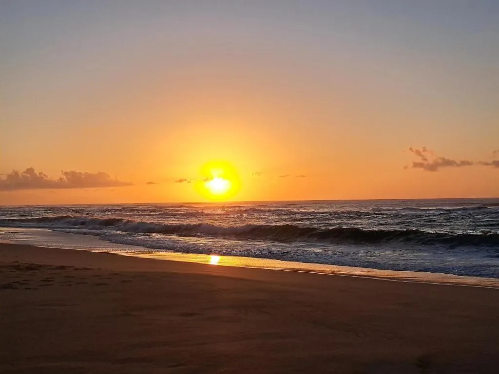 Golden sunset over the ocean with waves rolling onto sandy beach