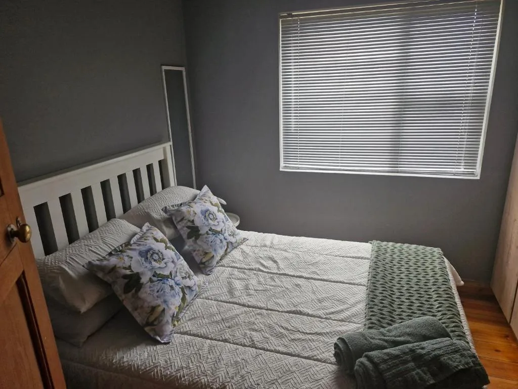 Bright bedroom with white headboard bed, floral pillows, and natural light