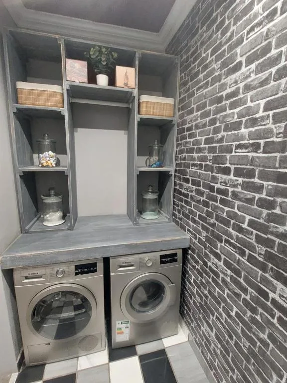 Modern laundry room with washer, dryer, and stylish brick accent wall