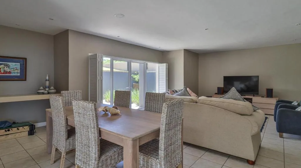 Open-plan living area with dining table, sofa, and TV entertainment setup