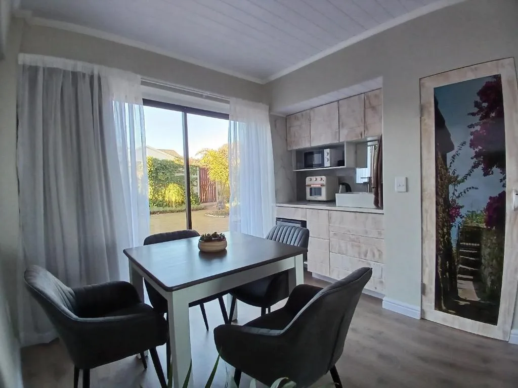 Modern dining table with black chairs and garden view through sliding doors