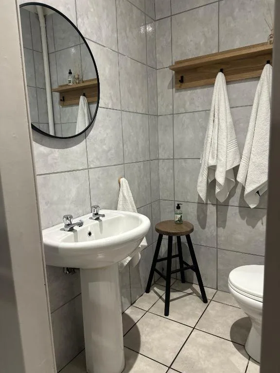 Modern bathroom with pedestal sink, round mirror, and white towels