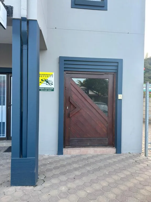 Modern white building entrance with dark blue trim and wooden door