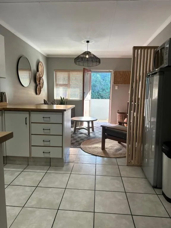 Open-plan kitchen with sage cabinetry, stainless steel fridge, and view into lounge area