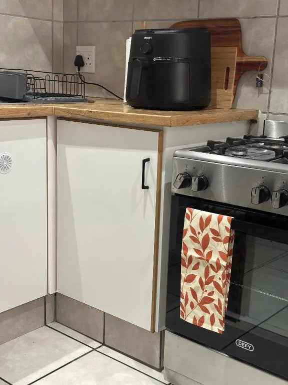 Modern kitchen with gas stove, wooden countertop, and black air fryer