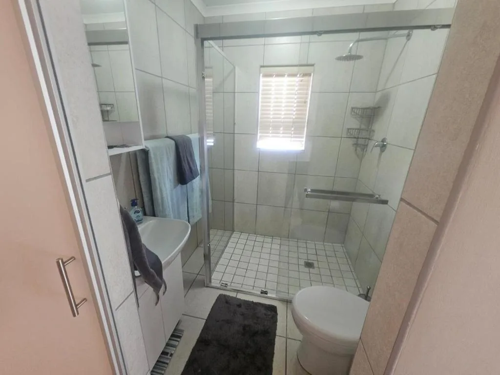 Modern bathroom with large walk-in shower, white tile, and toilet