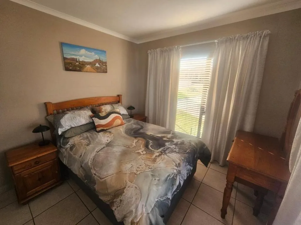 Bedroom with wooden bed, nightstand, and garden view through glass doors