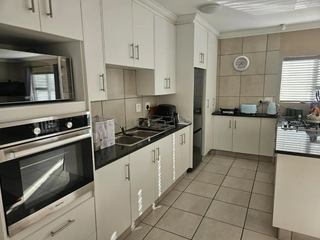 Modern kitchen with white cabinetry, black countertops, and stainless steel appliances