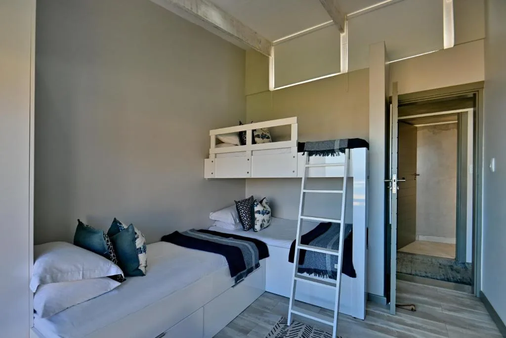 Modern bedroom with bunk bed and single bed, white furniture and storage