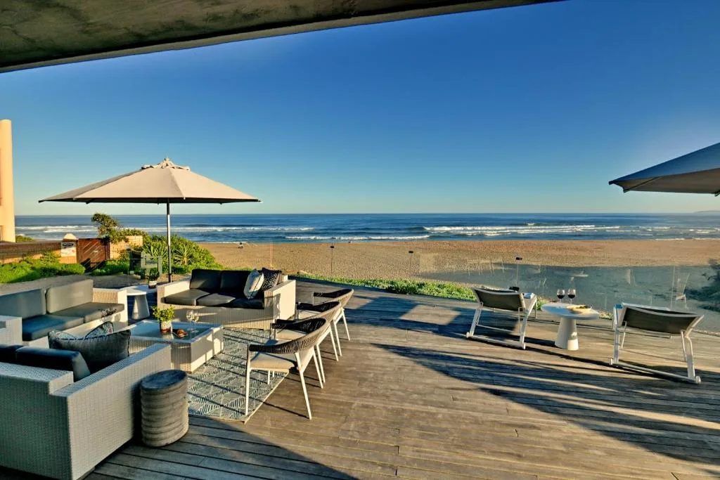 Beachfront deck with lounge seating, umbrellas, and ocean views