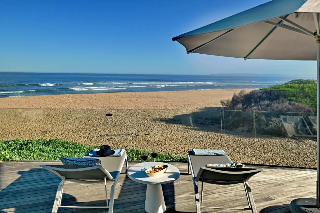 Beachfront deck with umbrella, loungers, and ocean view