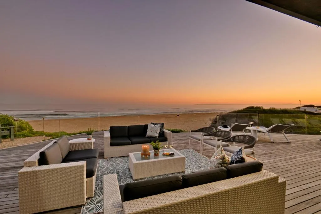 Beachfront deck with lounge seating, sunset ocean views, and beach access